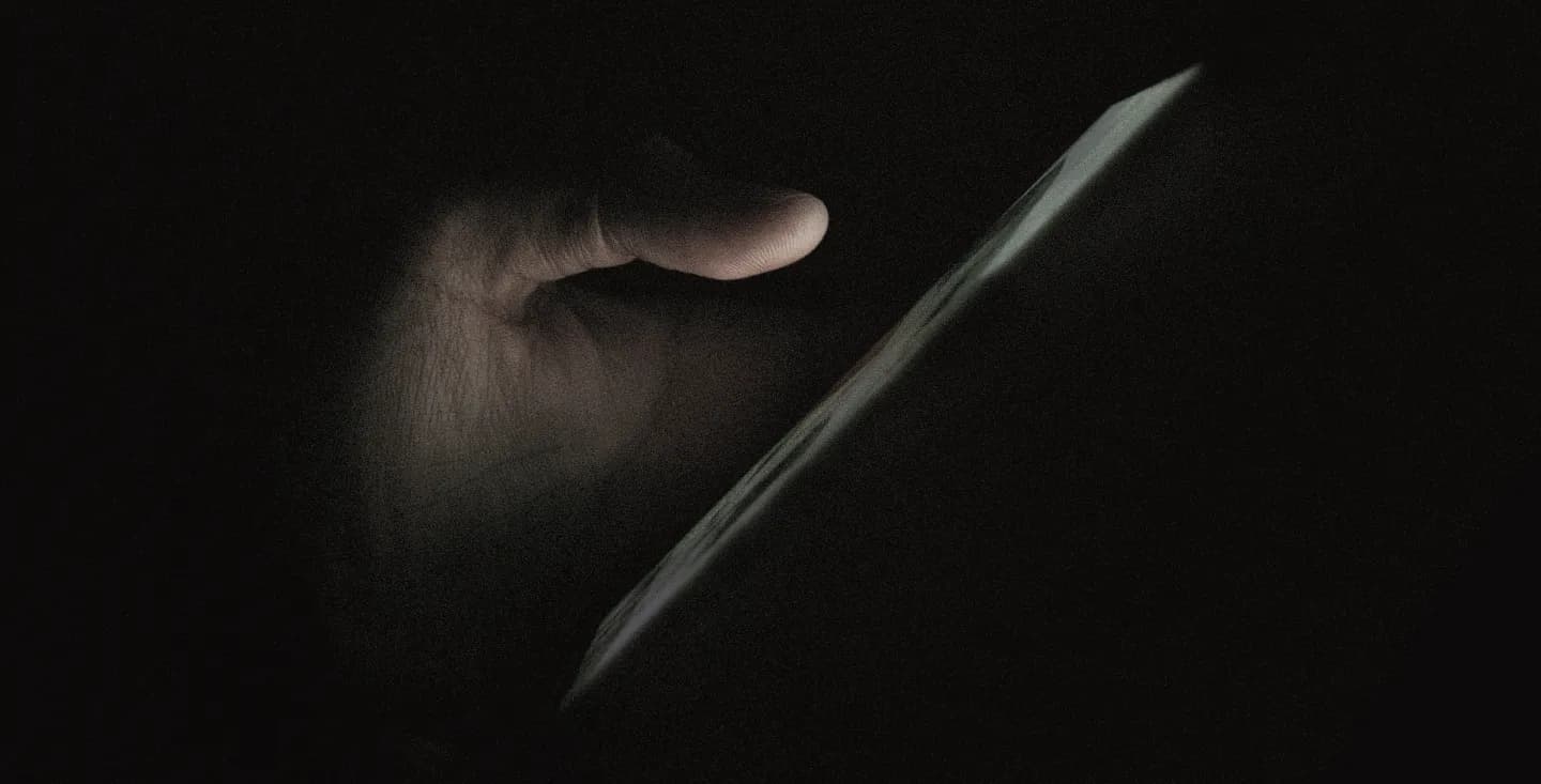 Hand holding a glowing phone in the dark