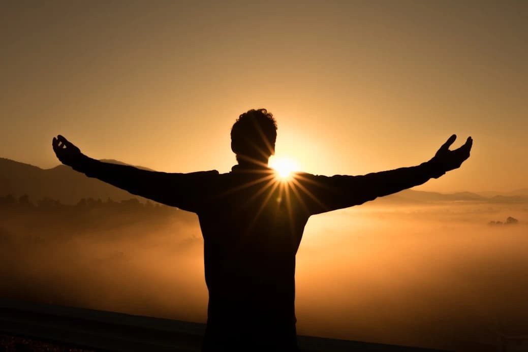 Silhouette facing the sunrise with open arms